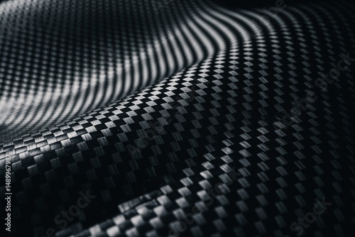 Close-up of textured black carbon fiber showcasing intricate patterns and smooth contours.