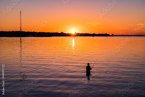 Fototapeta Naklejka Na Ścianę i Meble -  Silhouette of a man fishing at sunset at Lake Tawakoni State Park, Texas