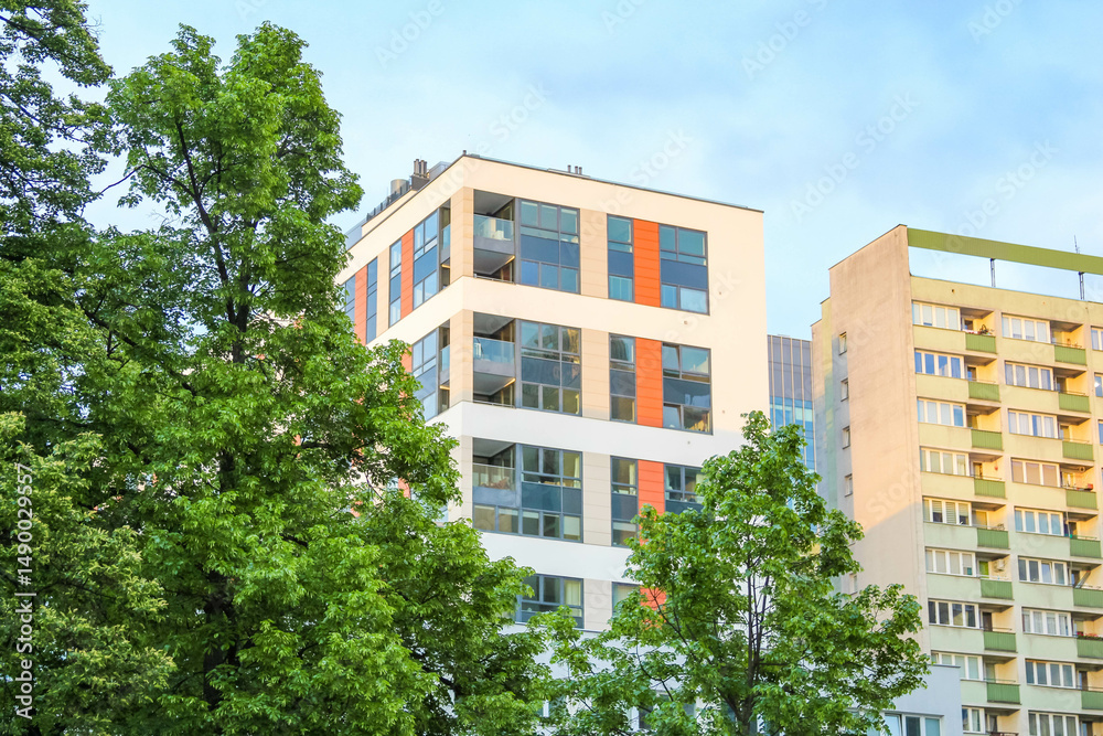 Fototapeta premium Modern Apartment Building with Distinctive Orange Accents Surrounded by Lush Green Trees