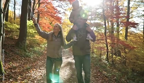 Family Autumn Stroll: A family enjoys a joyful walk amidst the vibrant autumn foliage, the father carrying a child on his shoulders, all bathed in warm sunlight.