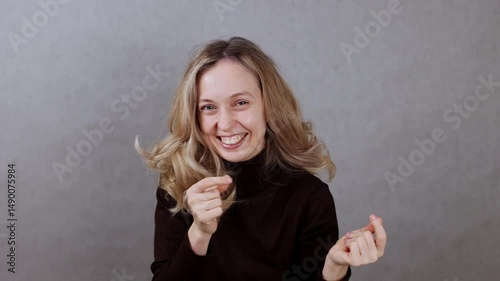 Cheerful young woman dancing on gray background, copy space