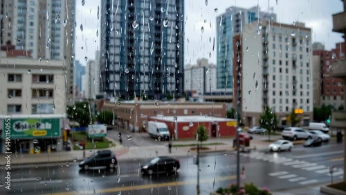 Rainy Day Cityscape View with Urban Buildings and Wet Ground Reflections Through Window Pane