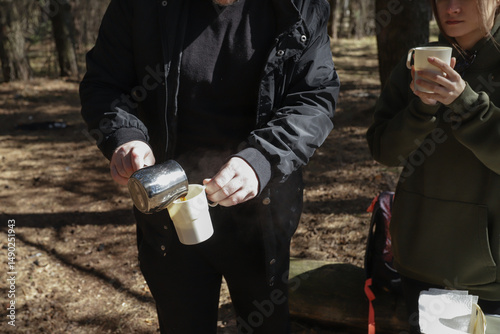 Картината върху платно Outdoor morning ritual in a pine forest as a couple shares a quiet drink; one po