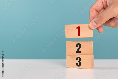 Concept of task priority and management. Priority of activities. A man hand place wooden cubes with number one, two and three