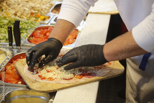 Elsässer Flammkuchen wird belegt mit Handschuhen