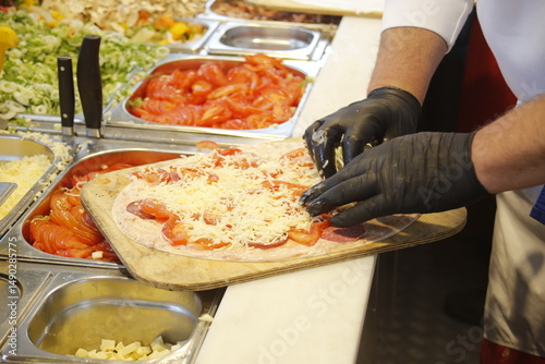 Elsässer Flammkuchen wird belegt mit Handschuhen