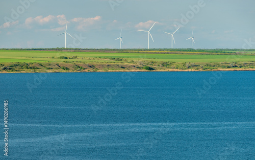panoramic view to blue lagoon and group of wind generators under spring sky with copy space in water