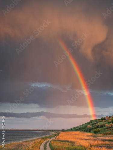 portrait view to burning clouds and rainbow with coastal ground road and copy space