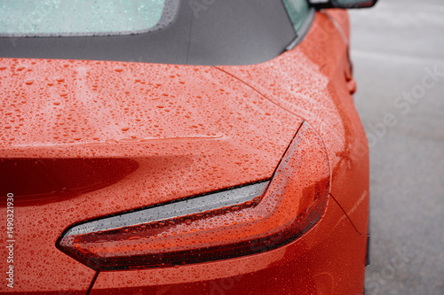 vibrant sports car rear in rain showcases sleek red body and modern tail light design. wet vehicle surface emphasizes dynamic curves, ideal for automotive enthusiasts and advertisers photo
