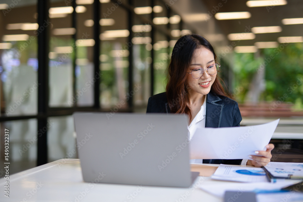 Asian businesswoman in suit using mobile phone while standing in front of modern business building. Asian businesswoman in suit using mobile phone while standing in front of modern business building.