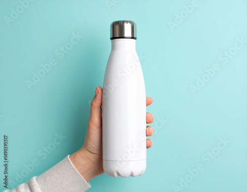 Close-Up of Female Hand Holding White Reusable Stainless Steel Thermo Water Bottle Outdoors photo