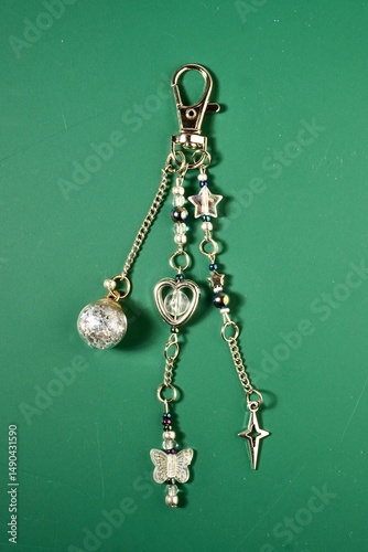 Fotografi Silver gray beautiful bag charm decorative keychain isolated on vertical ratio green background