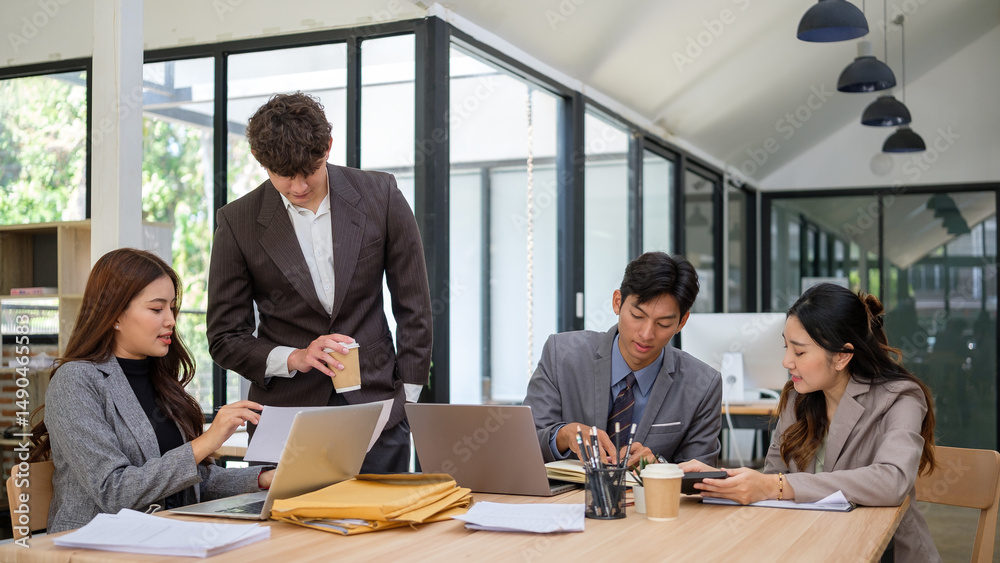 Obraz premium Group of diverse business professionals collaborating around a shared desk in a modern office setting.