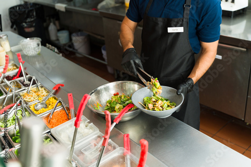 Billede på lærred Cook preparing a fresh salad at salad bar restaurant