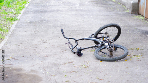 A black bicycle lies on the pavement after a road accident. No people. Concept on the topic of safe road traffic.