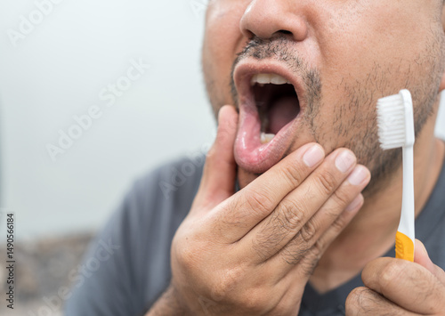 Man look in mirror touch cheek with hand and feels pain while brushing teeth due cavity or caries. Toothache dental check up oral care need toothpaste for sensitive tooth. Dental health care concept