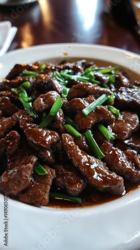 close-up of rich mongolian beef dish in savory sauce with scallions and ambient background