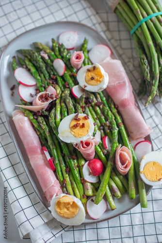 Fresh organic asparagus wrapped in Parma ham on a cutting board