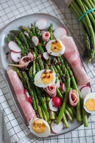 Fresh organic asparagus wrapped in Parma ham on a cutting board