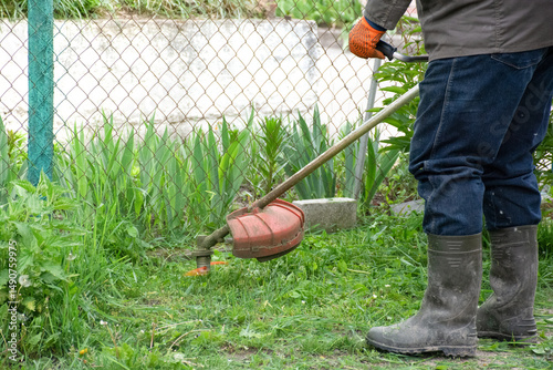 Man mowing grass with hand mower, working in garden near house. High quality photo