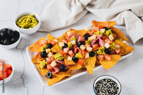 Appetizer plate with nachos, salami, cheese, tomato and black olives on the table
