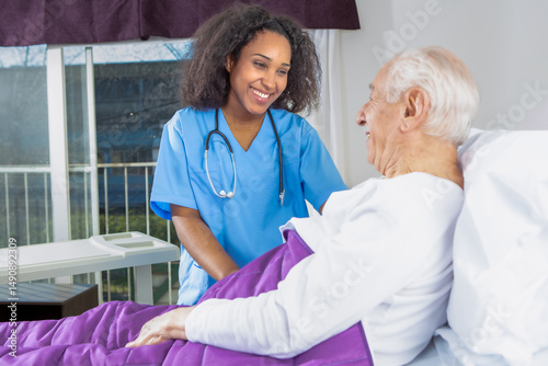 Foto Smiling nurse comforting elderly patient lying in hospital bed during compassion