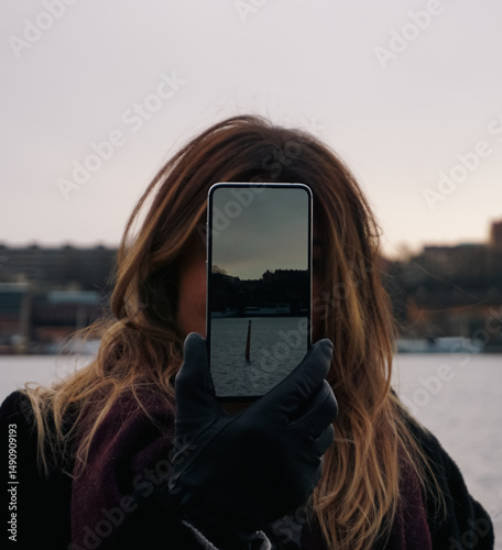 A woman holding a mobile phone in front of her face