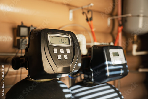 Modern water filtration and heating system installed in a utility room, featuring digital control panels and various tanks and pipes under warm indoor lighting.