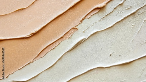 Close-up of a swatch of a foundation or concealer. the swatch is made up of multiple layers of different shades of foundation, ranging from light beige to dark beige.