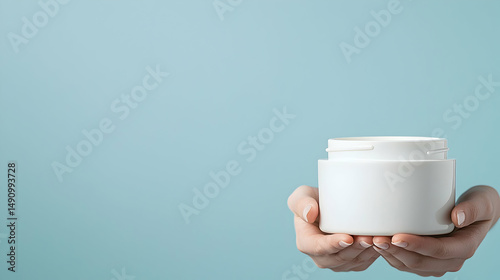 Woman's Hands Holding a White Cream Jar Against a Light Blue Background