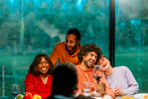 Canvas Print Happy friends laughing and raising a toast during a dinner party