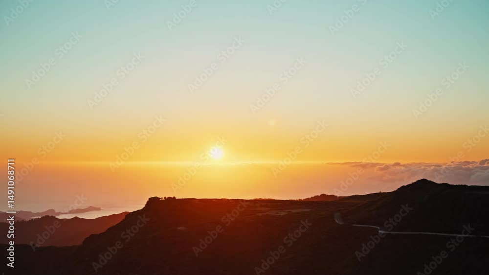 Mountain valley with dense vegetation above cloud layer at golden hour