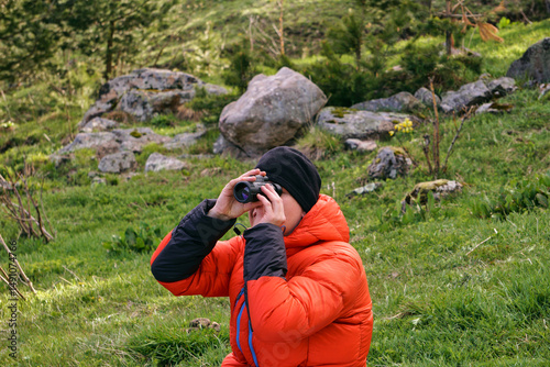 A man looks intently at the mountains through a monocular