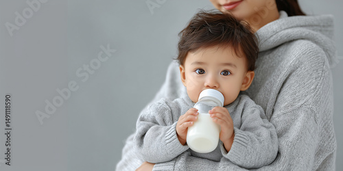 A tender moment of motherly care. A baby drinking from a bottle while being cradled in their mother's arms