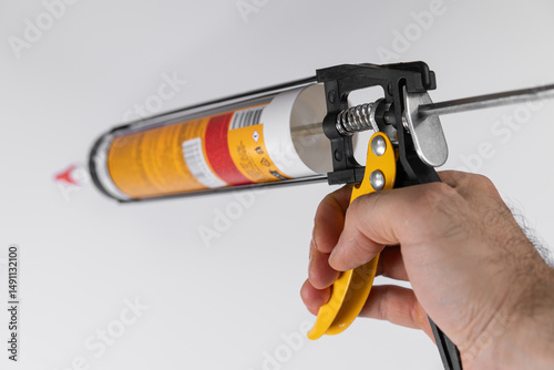Hand holding caulking gun ready for application of sealant in home improvement project