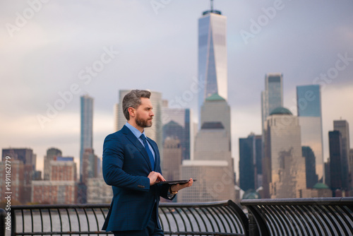 Businessman with laptop in New York City. Financial Manhattan. Office worker hold laptop against cityscape in NYC. Business man in suit using laptop outdoor. Office work on laptop. Hispanic manager.