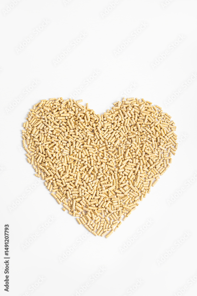 Beige granules in the shape of heart on white background. Vertical. Filler for cat litter box, fuel pellets or food for birds or goats Beige granules in the shape of heart on white background. Vertical. Filler for cat litter box, fuel pellets or food for birds or goats