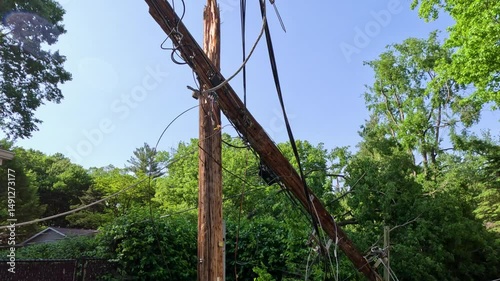Power line completely destroyed by a fallen tree following severe storms and high winds. The wooden pole has been snapped in half created dangerous conditions and a power outage. Midwest, USA.