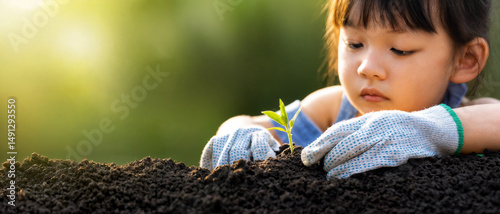 The child is planting flowers in the garden. Selective focus. Kid. High quality photo