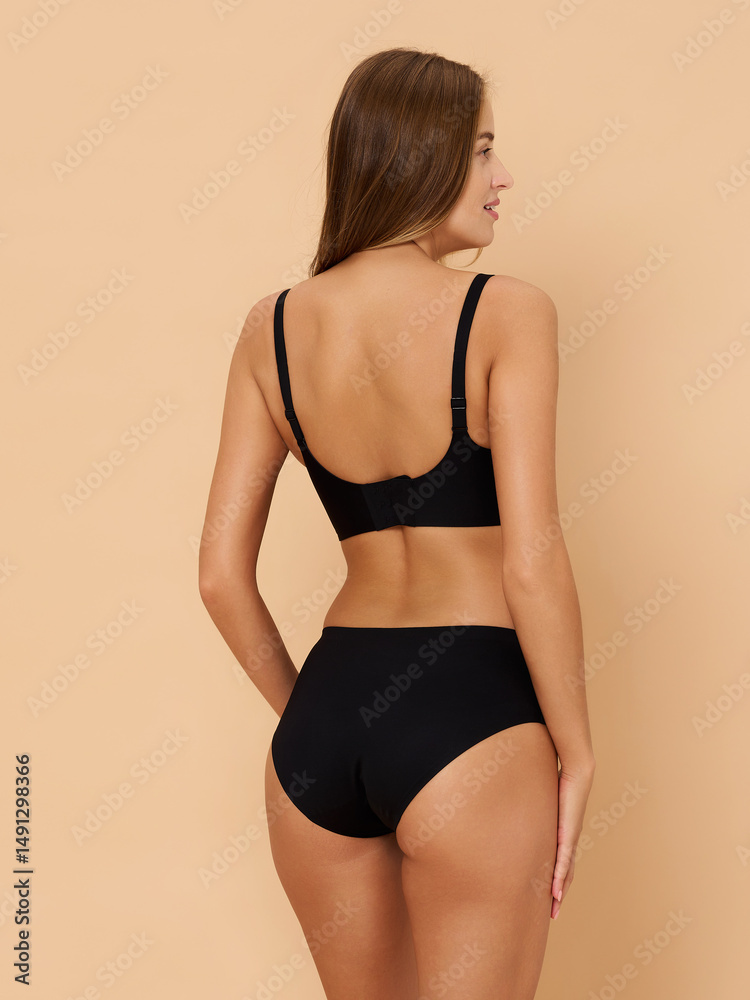 Fototapeta premium Girl model in underwear posing in studio on beige background.