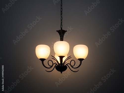 Elegant chandelier with three glowing bulbs illuminating a dark space.
