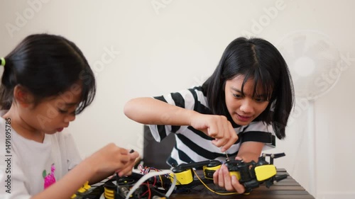 Wallpaper Mural Two Asian girls working together on robotics project at home. Promoting STEM education, teamwork, coding, and problem-solving through hands-on engineering and creative learning. Torontodigital.ca