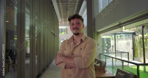 Wallpaper Mural Man standing in office hallway with arms crossed, confident expression, assertive posture in modern workplace, strength and leadership presence Torontodigital.ca