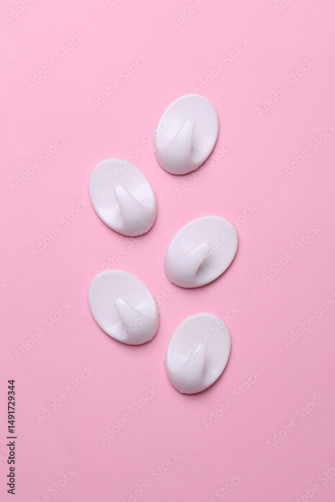 White plastic hanger hooks on pink background White plastic hanger hooks on pink background