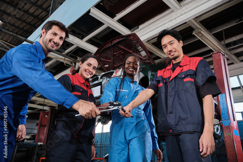 Harmonious professional mechanic teamwork, multiracial engineers with wrenches united, cheerful, and happy smile in fix car garage, maintenance service jobs in automotive transport industry station.