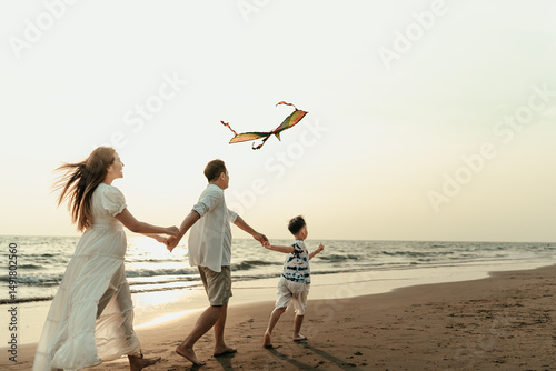 Children flying kites on the beach with family during vacation, travel, long weekend, summer or other holidays. They are happy to spend time together.