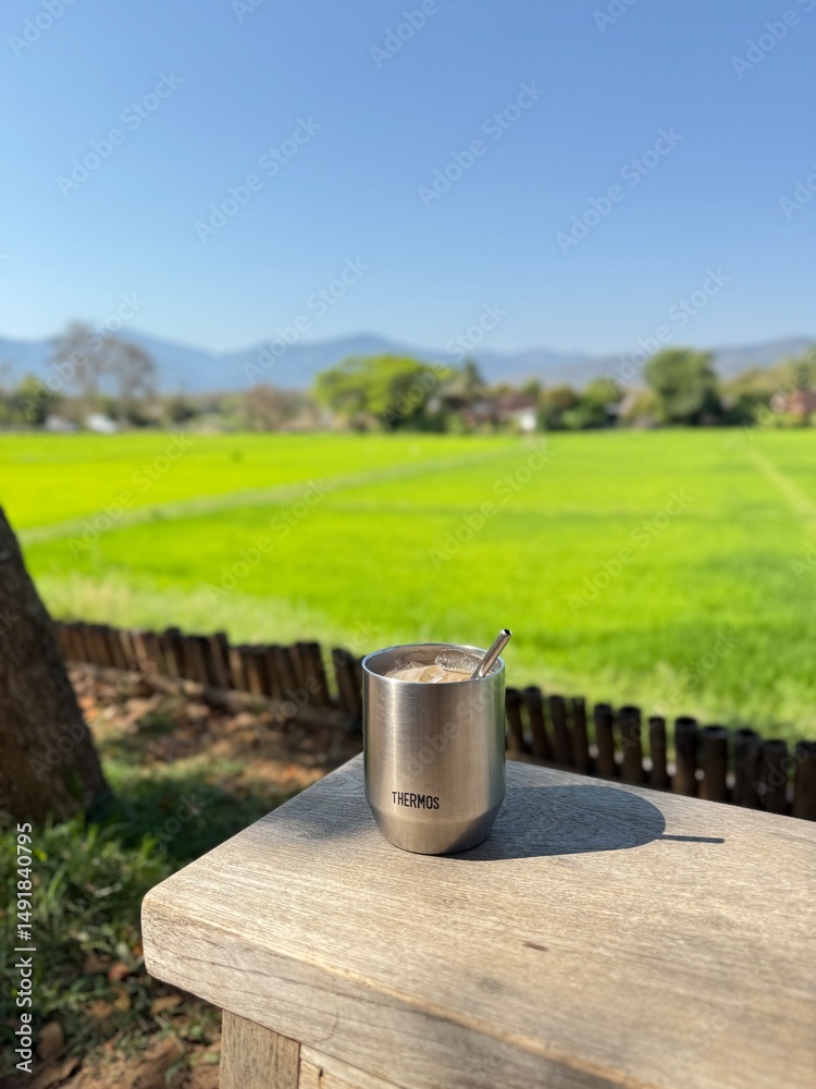 A cup of coffee on wood bench with green feild view A cup of coffee on wood bench with green feild view