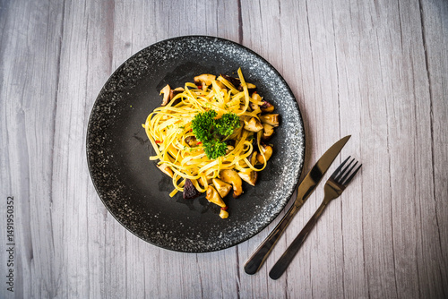 Mushroom Aglio Olio pasta served on a black plate on a table
