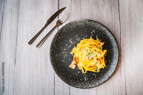 Carbonara with ham cream and cheese served on a black plate