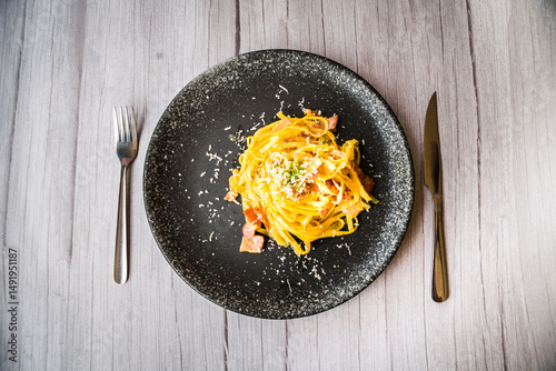Carbonara with ham cream and cheese served on a black plate